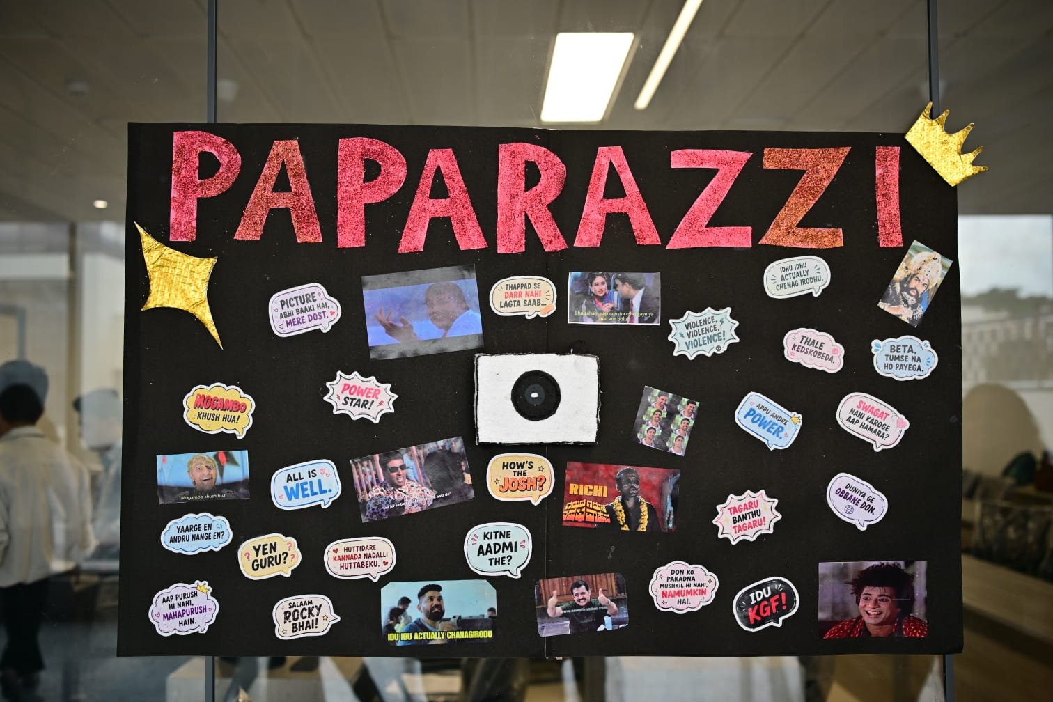 Handmade Paparazzi-themed display board with film and meme speech bubbles, created by journalism and mass communication students for a campus event at PES University
