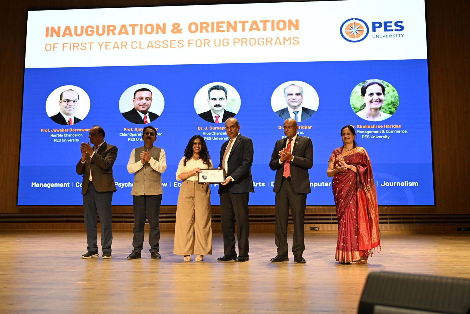 Student receiving a merit scholarship certificate from PES University leadership at the inauguration of first-year undergraduate classes