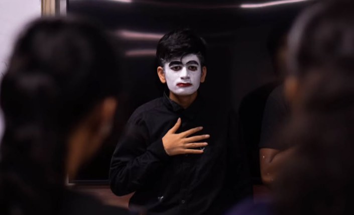 Student in mime face paint performing a solo piece during a communication through mime workshop at PES University