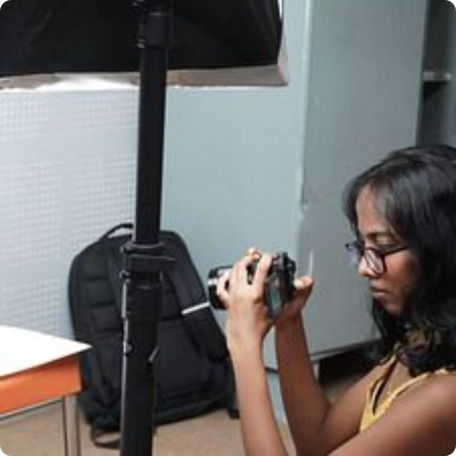 Journalism and mass communication student photographing products under studio lighting during a product photography session at PES University