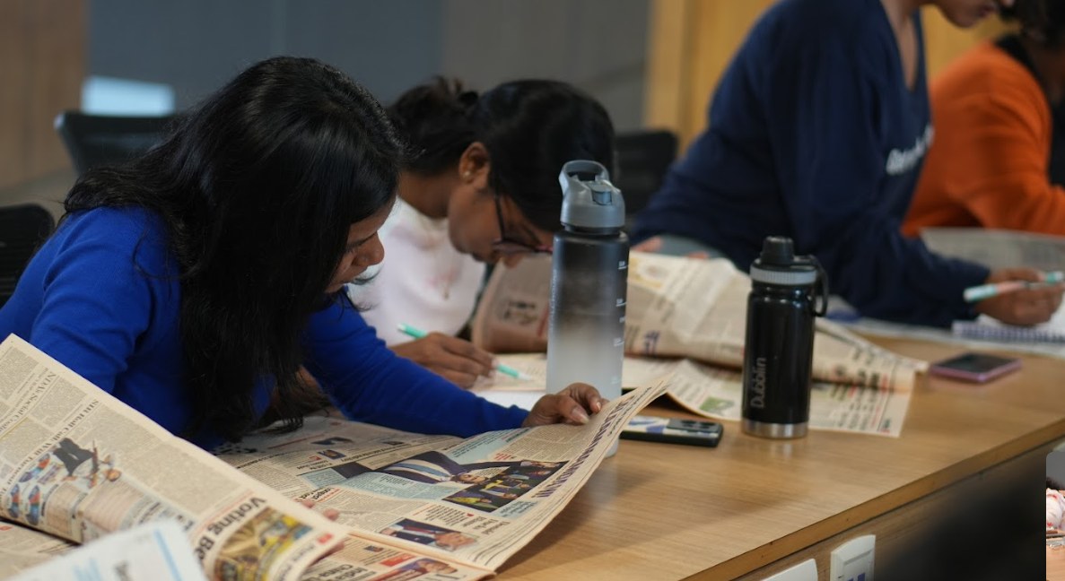 Students reading broadsheet newspapers and taking notes during a journalism class at PES University Bengaluru